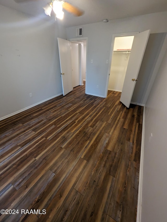 unfurnished bedroom featuring dark wood-style floors, baseboards, visible vents, and a ceiling fan