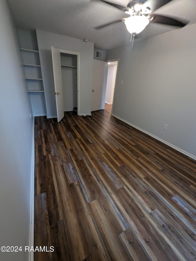 unfurnished bedroom featuring ceiling fan, visible vents, baseboards, a closet, and dark wood finished floors