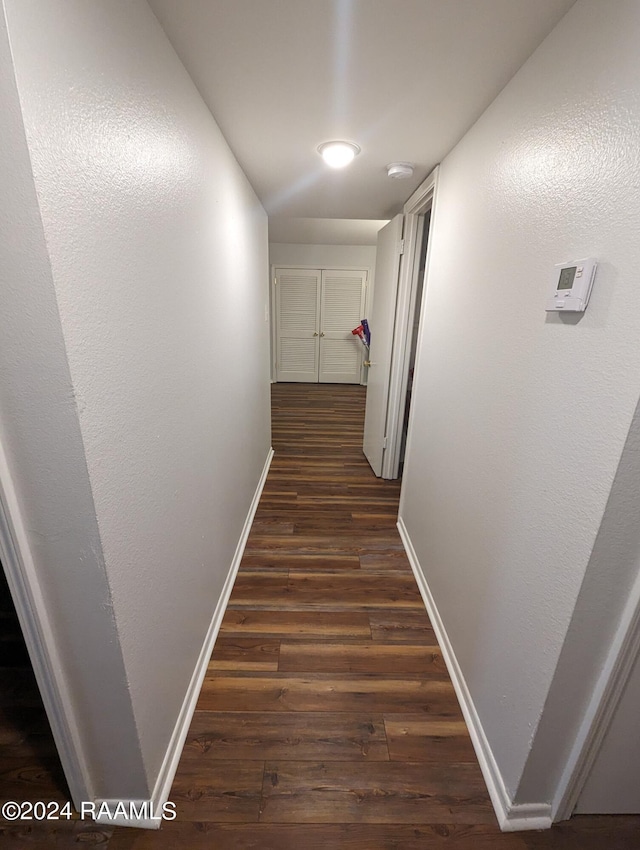 hallway featuring dark wood-style floors and baseboards