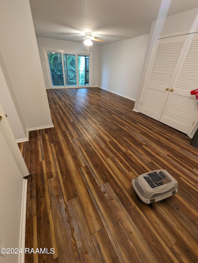 unfurnished living room with a ceiling fan, baseboards, and dark wood-style flooring