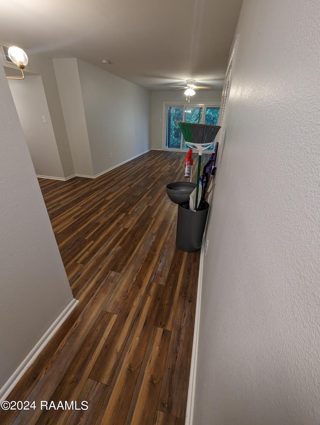 interior space with ceiling fan, baseboards, dark wood finished floors, and a textured wall