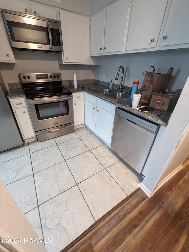 kitchen with stainless steel appliances, dark countertops, white cabinets, and a sink