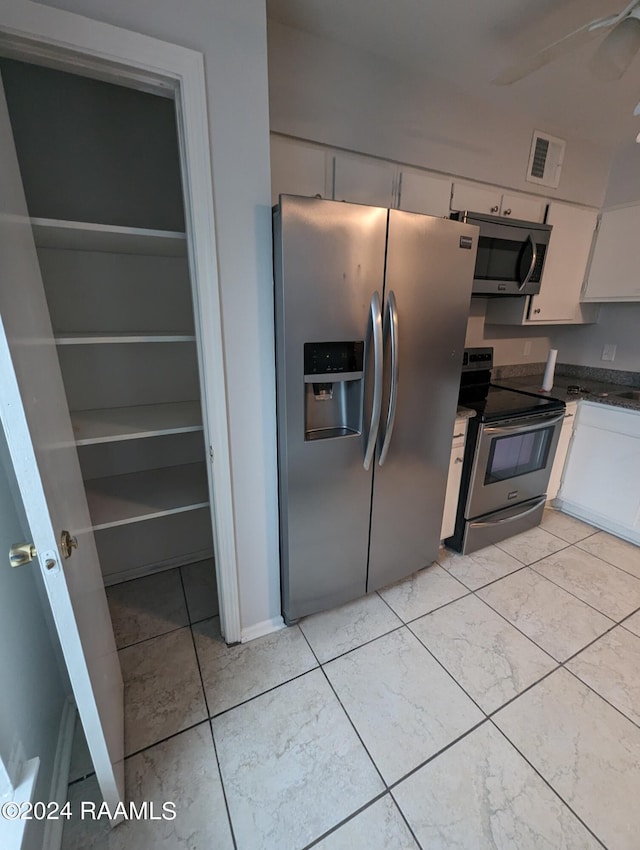 kitchen with stainless steel appliances, dark countertops, white cabinetry, and visible vents