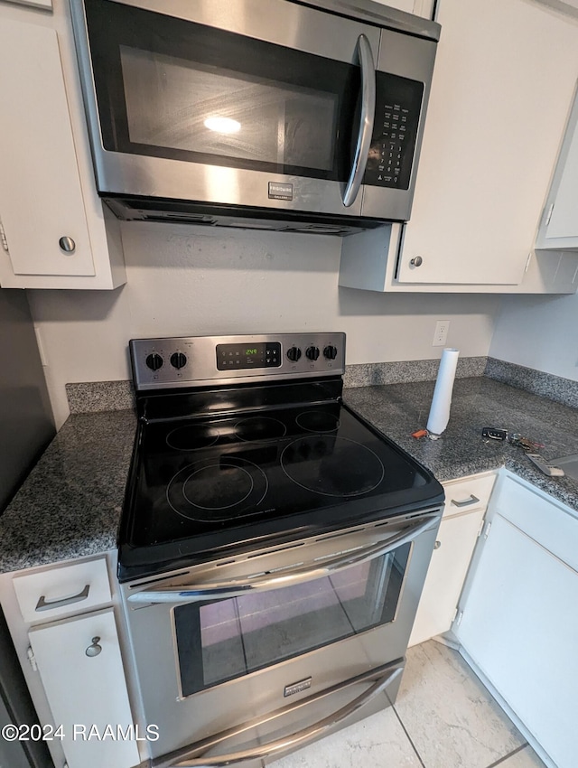 kitchen featuring appliances with stainless steel finishes, marble finish floor, white cabinets, and dark stone countertops