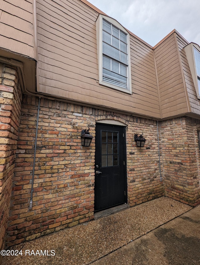 property entrance featuring mansard roof and brick siding