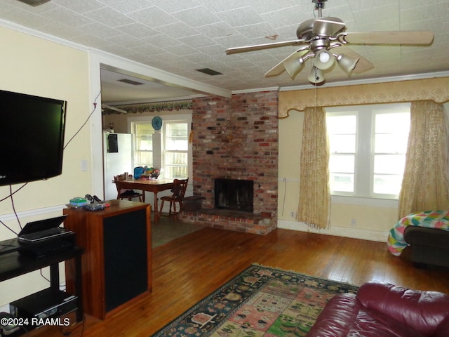 living room featuring ceiling fan, a fireplace, wood-type flooring, brick wall, and ornamental molding