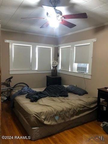 bedroom featuring hardwood / wood-style flooring, ornamental molding, and ceiling fan