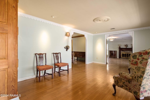 living area with hardwood / wood-style flooring and ornamental molding