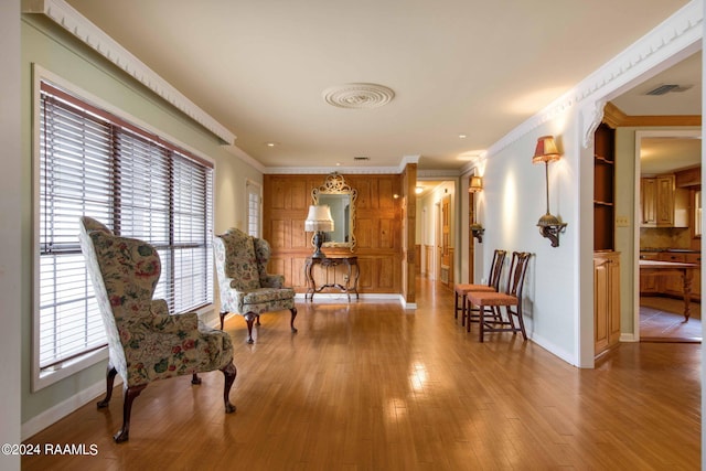 living area with hardwood / wood-style flooring and crown molding