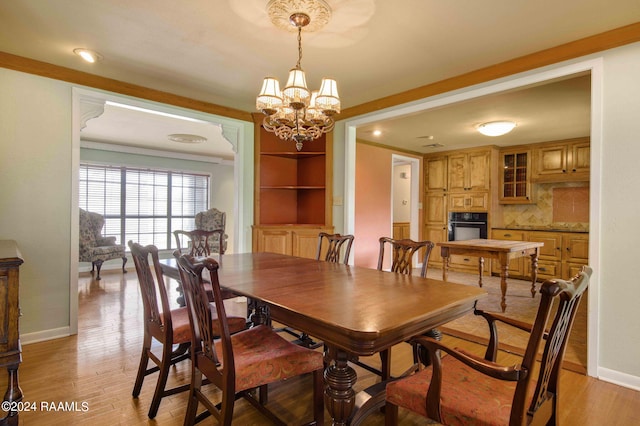 dining room featuring light hardwood / wood-style flooring, ornamental molding, and a notable chandelier