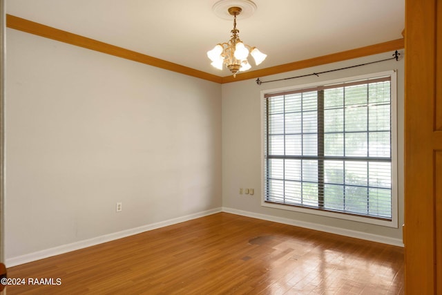 spare room featuring hardwood / wood-style flooring, a notable chandelier, and ornamental molding