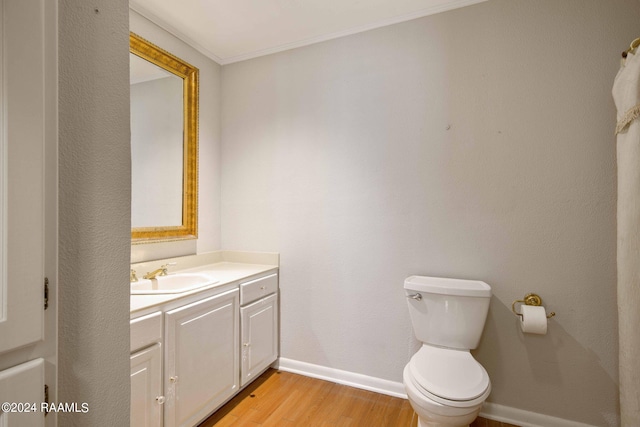 bathroom with crown molding, vanity, wood-type flooring, and toilet