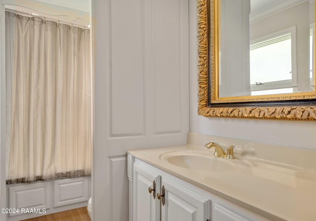 bathroom with crown molding, vanity, and hardwood / wood-style flooring