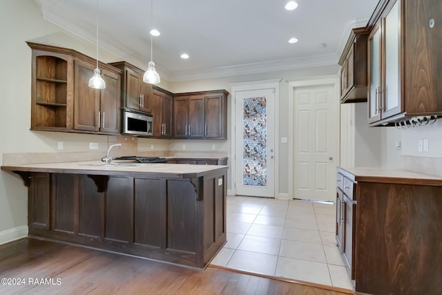 kitchen with hanging light fixtures, kitchen peninsula, a breakfast bar area, dark brown cabinets, and ornamental molding