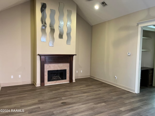 unfurnished living room featuring dark hardwood / wood-style floors, a tile fireplace, and vaulted ceiling