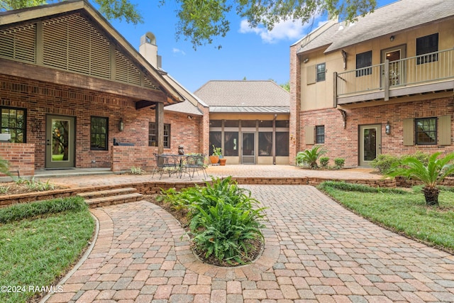 rear view of property with a balcony, a patio area, and a sunroom