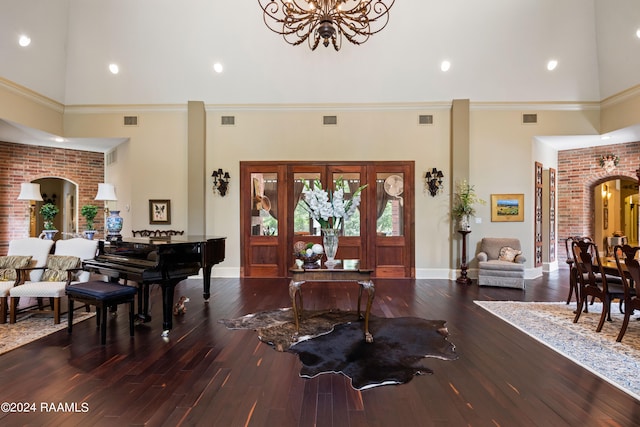 entryway featuring a notable chandelier, wood-type flooring, ornamental molding, and a high ceiling