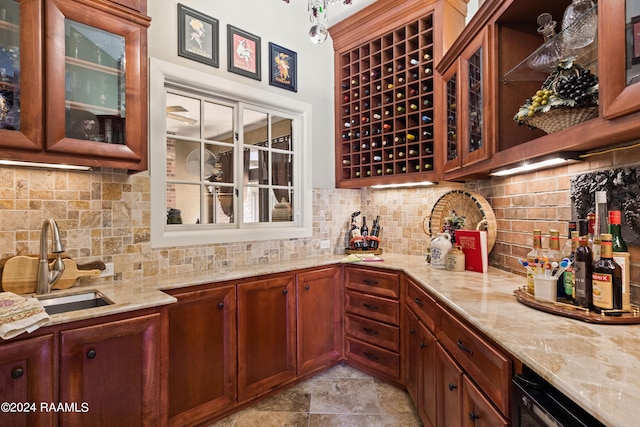 interior space with backsplash, light stone counters, and sink