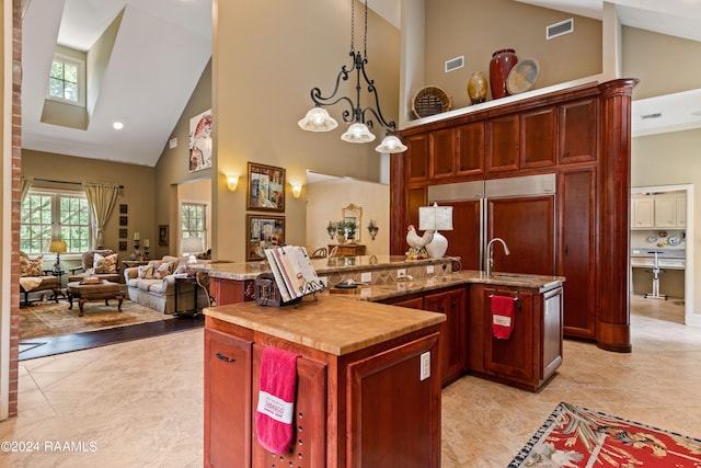 kitchen featuring high vaulted ceiling, an island with sink, decorative light fixtures, and an inviting chandelier