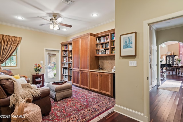 living room featuring ceiling fan, ornamental molding, and dark wood-type flooring