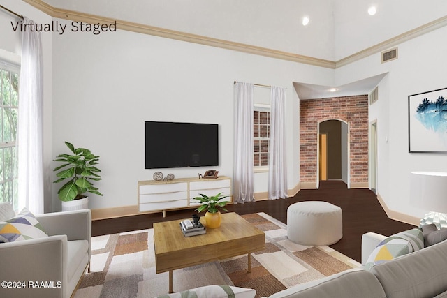 living room featuring wood-type flooring, ornamental molding, and a towering ceiling