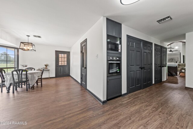 kitchen featuring dark hardwood / wood-style flooring, wall oven, black microwave, and a wealth of natural light