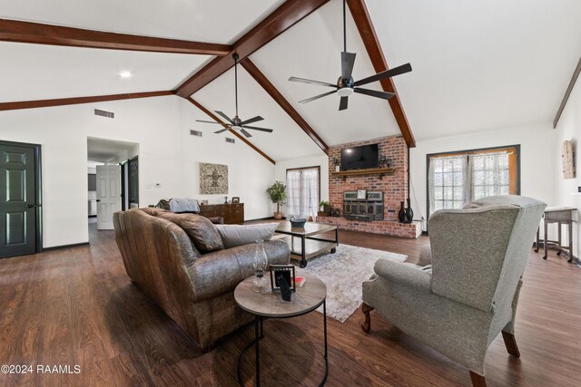 living room with beam ceiling, a wood stove, dark wood-type flooring, and a healthy amount of sunlight