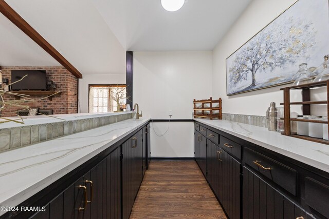 kitchen with light stone counters, dark wood-type flooring, and sink