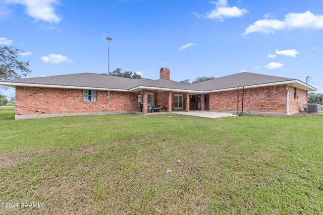 rear view of property featuring a lawn, central air condition unit, and a patio