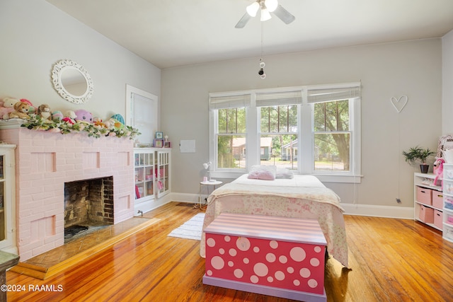 bedroom featuring a fireplace, ceiling fan, and hardwood / wood-style floors