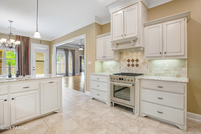 kitchen with light stone counters, white cabinets, pendant lighting, high end range, and crown molding