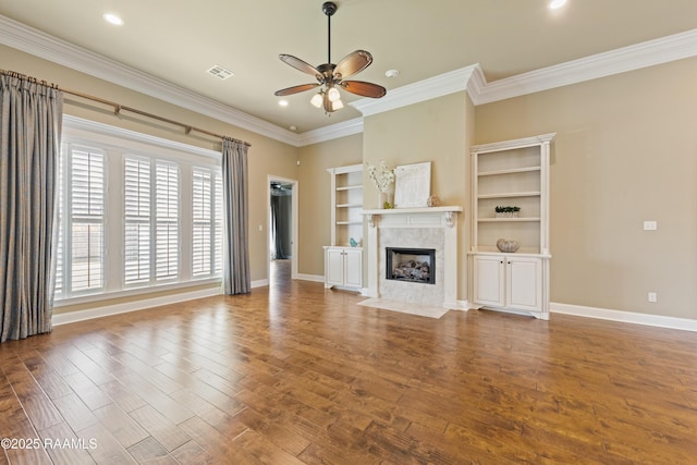 unfurnished living room with ceiling fan, a premium fireplace, wood finished floors, and baseboards