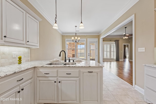 kitchen featuring tasteful backsplash, ornamental molding, a peninsula, a sink, and light tile patterned flooring