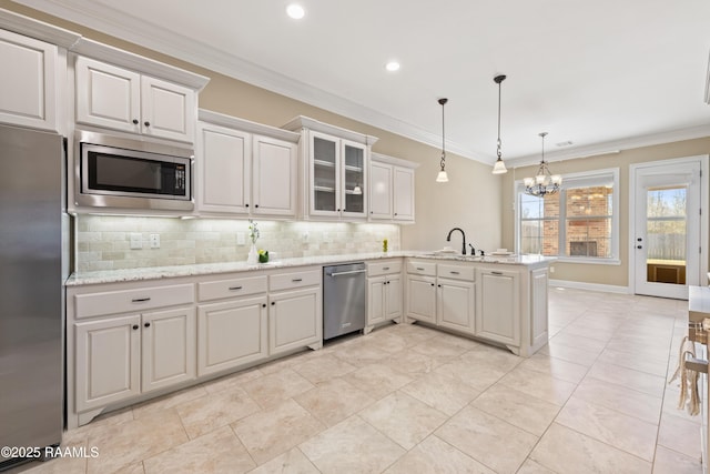 kitchen with stainless steel appliances, backsplash, ornamental molding, a sink, and a peninsula