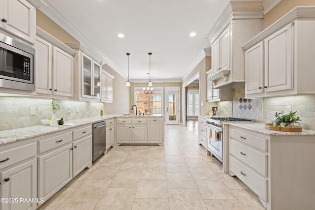 kitchen featuring glass insert cabinets, a peninsula, stainless steel appliances, crown molding, and backsplash