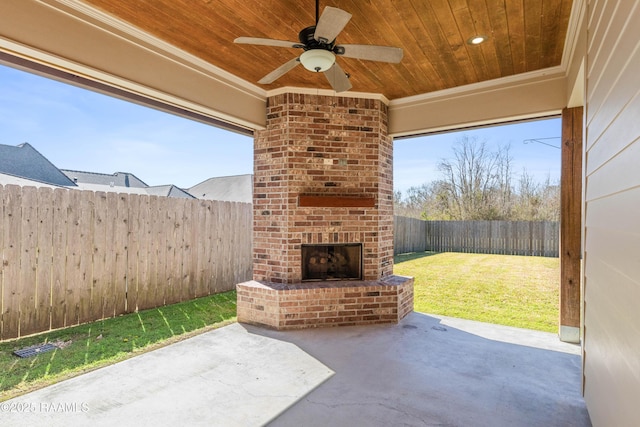 view of patio with an outdoor brick fireplace, a fenced backyard, and a ceiling fan