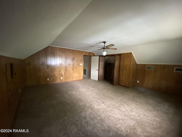 bonus room featuring carpet flooring, ceiling fan, wood walls, and lofted ceiling