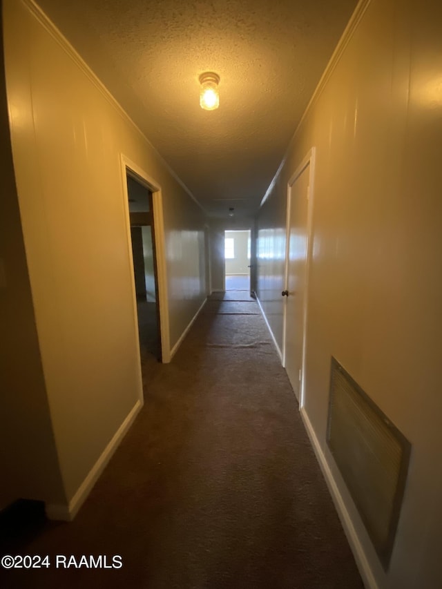 hall with dark colored carpet, a textured ceiling, and crown molding