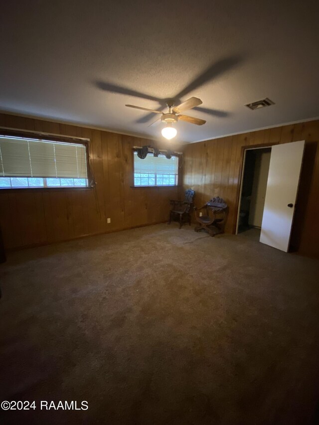 unfurnished bedroom featuring carpet, ceiling fan, and wooden walls