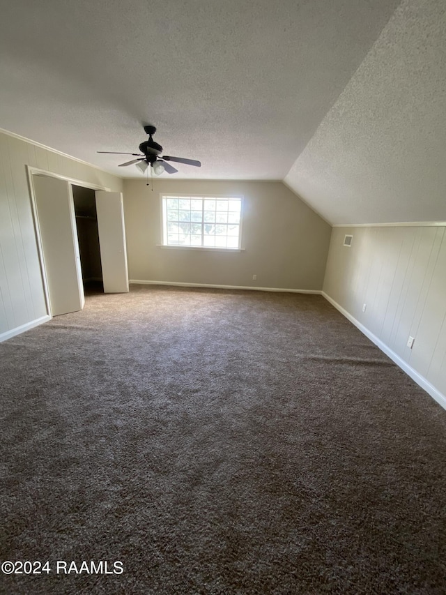 additional living space with carpet, a textured ceiling, vaulted ceiling, and ceiling fan