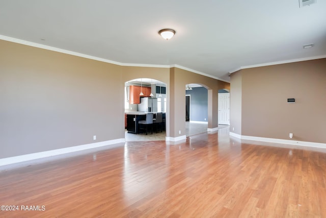 empty room featuring light wood-type flooring and ornamental molding