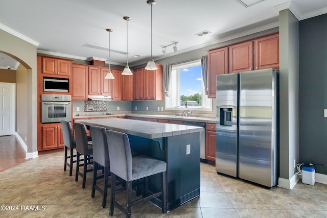 kitchen featuring ornamental molding, a kitchen island, hanging light fixtures, and appliances with stainless steel finishes