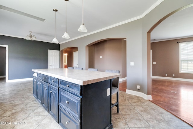 kitchen featuring decorative light fixtures, a kitchen island, light tile patterned flooring, and blue cabinets