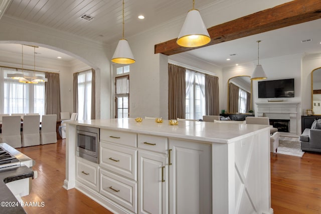 kitchen with a wealth of natural light, stainless steel microwave, and hardwood / wood-style floors