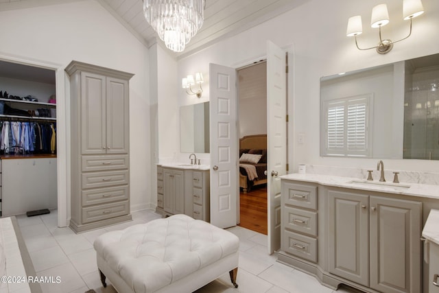 bathroom with tile patterned floors, vanity, vaulted ceiling, and an inviting chandelier