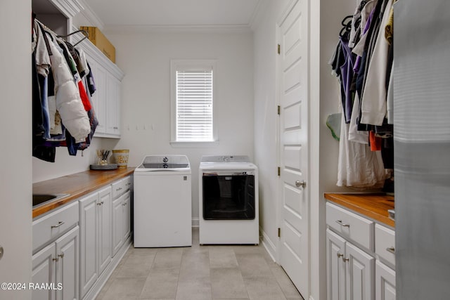 clothes washing area with sink, cabinets, separate washer and dryer, and ornamental molding