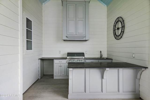 kitchen featuring gray cabinets, lofted ceiling, kitchen peninsula, and wooden walls