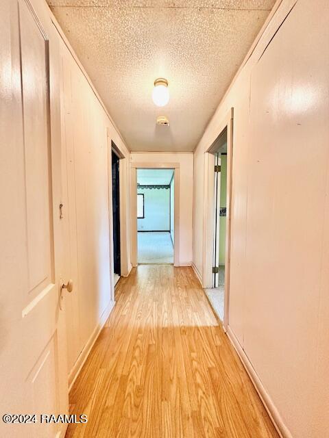 hall with light hardwood / wood-style floors and a textured ceiling