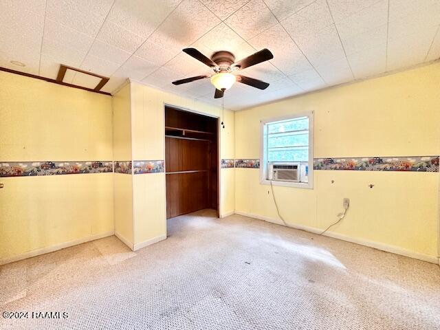 unfurnished bedroom with a closet, carpet flooring, ceiling fan, and cooling unit