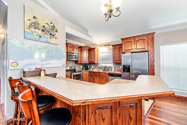 kitchen with kitchen peninsula, a kitchen breakfast bar, tasteful backsplash, stainless steel appliances, and vaulted ceiling